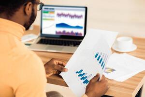Busy Day. Rear view of afro trader working with charts and market reports on computer screen in office, free space photo