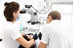 Difficult cases in stomatology. Back view of two dentists making treatment in modern dental office photo