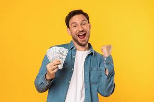 A man is seen holding a large bunch of money in his hands. The money is neatly stacked and the mans expression is one of satisfaction and success. photo