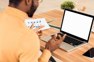 Problems At Work. Rear view of black manager gesturing, using laptop with white blank screen, mock up, copyspace photo