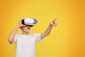 Wow, its amazing. Boy experiencing virtual reality, gesturing on orange studio background, copy space photo