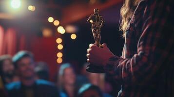 A person stands in front of an audience, proudly holding a shiny trophy, celebrating a notable achievement in a vibrant, intimate setting. photo