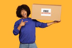 A man stands holding a cardboard box with a prominent Free Delivery sign on it. The man appears to be ready to deliver the package to its intended recipient photo