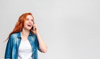 A woman with vibrant red hair is engaged in a phone conversation on her mobile device. She appears focused and animated as she communicates verbally through the phone, copy space photo