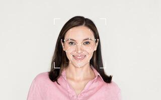 A woman smiles while facial recognition technology maps her features in a plain environment. photo