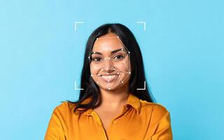 Indian woman smiles confidently with facial recognition patterns displayed on her face, set against a bright blue backdrop. photo