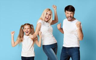 A young family of three, including a mother, father, and daughter, are joyfully celebrating their success, shown by their elated expressions and raised fists. photo