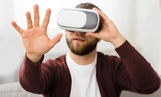 A bearded man is wearing a virtual reality headset, immersing himself in a digital environment. His facial features are partially obscured by the device as he interacts with the virtual world photo
