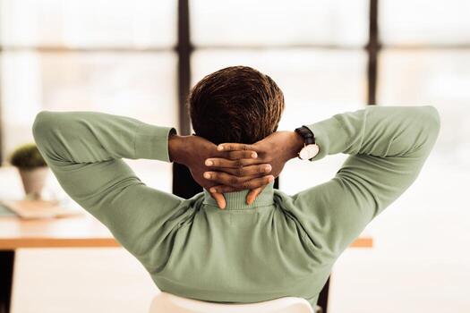 Relax In Office. Back view of black businessman having rest after solving problem, completing all the tasks, copy space photo