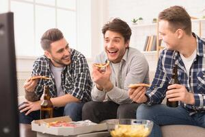 Three mates are sharing pizza and laughter in a bright living room, showcasing european men enjoying their friendship photo