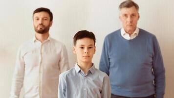 Misunderstanding Between Generations. Boy, Father And Grandfather Standing Looking At Camera Over White Background. Panorama, Selective Focus photo