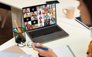 A laptop screen displays a conference call with multiple participants of various backgrounds and ethnicities, all appearing in separate squares. photo