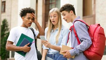 Failed tests. Shocked classmates checking exam results on smartphone, resting in college campus photo