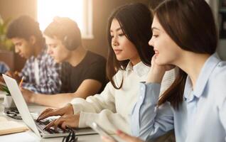 Student girls networking on laptop in library, doing project together photo
