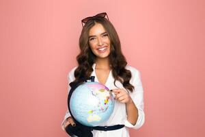 A woman standing, holding a globe in her hands with a serious expression on her face. She is looking down at the globe, fingers gently wrapped around it, showing a sense of care and responsibility. photo