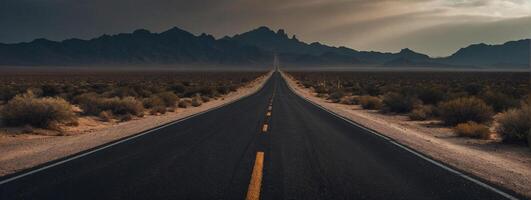 An empty road in the desert with mountains in the background photo