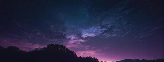 A purple sky with stars and clouds over a mountain photo