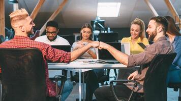 Colleagues in a loft office engage in teamwork, with two men sharing a fist bump, highlighting a positive and collaborative work environment. photo