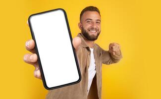A man holds a cell phone in his hand, showing a focused expression. His hand grips the phone firmly as he looks intently at the screen, mockup copy space photo