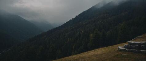 A person sitting on a bench in the middle of a mountain photo