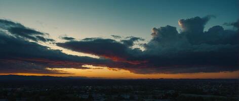 A sunset over a city with clouds and a mountain in the background photo