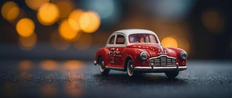 A red toy car sitting on a table with blurred lights photo