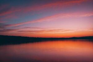 A sunset over a lake with a sky and clouds photo