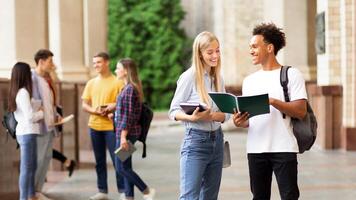 Happy classmates preparing for lecture in university campus, studying with books outdoors, free space photo
