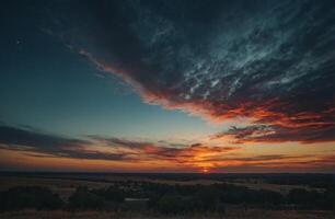 A sunset over a field with clouds and trees photo