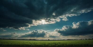 A green field with clouds and sun shining through photo