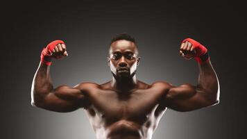 A shirtless man with red hand wraps flexes his bicep muscles in a studio setting. photo
