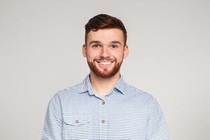 Portrait of smiling bearded millennial guy wearing casual shirt posing isolated on beige studio background photo
