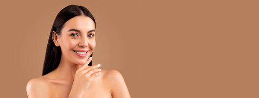 Aesthetic medicine and cosmetic surgery concept. Headshot of attractive long-haired brunette half-naked lady demonstrating her young smooth skin, touching face and smiling at camera, copy space photo
