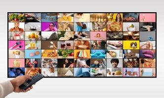 A hand holds a black remote control in front of a television screen that is displaying a variety of colorful images. The images are organized in a grid pattern and feature various scenes of people photo