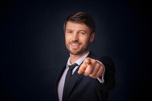 You're Next. Confident Businessman Pointing Finger Smiling At Camera Over Black Background. Studio Shot, Free Space photo