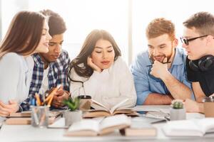Multiracial students at a library table use books to enhance their learning. The group's dynamic interaction embodies a modern, inclusive educational environment. photo