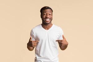 Look At Me. Black Man Pointing Fingers At Himself Smiling At Camera Standing Over Yellow Studio Background photo