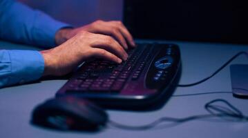 Cropped of a persons hands typing on a black keyboard. The image is taken at night, and the light from the computer screen illuminates the keyboard and the persons hands photo