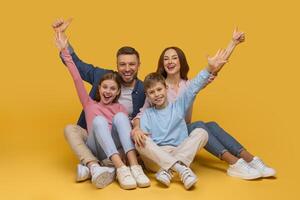 A joyful family sits closely together with arms raised in a celebratory gesture, smiling enthusiastically. A father and mother are behind their daughter and son, all sharing a moment of happiness photo