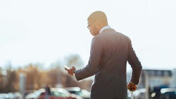 Black man business traveler is on the phone outside a contemporary airport. The mood is efficient and focused, showing the blend of travel and work in a sleek environment. photo
