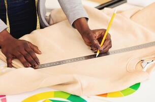 A person is shown in the image measuring a piece of cloth using a ruler, focusing intently on accurately determining the length of the fabric, cropped photo