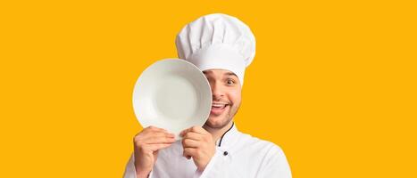 Funny Cook Man Covering Eye With Plate Looking At Camera Standing Over Yellow Studio Background. Panorama photo