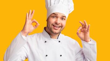 Happy Chef Man Gesturing Ok Recommending Recipe Standing On Yellow Studio Background. Panorama photo