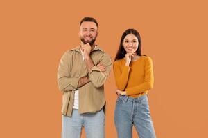 A man and a woman are standing side by side, looking towards the camera. They appear to be in a casual setting, with neutral expressions on their faces. photo