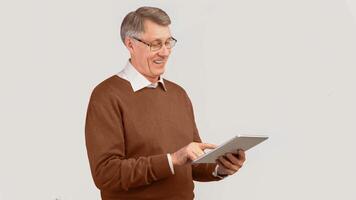 Great App. Contented Senior Man Using Tablet Computer Browsing Internet Standing Over Gray Background. Studio Shot, Panorama photo