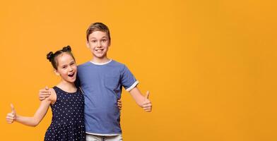 Approved by kids. Cheerful little boy and girl showing like gesture, orange studio background photo