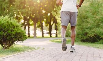 A man jogs down a brick path in a park, surrounded by greenery and trees. photo