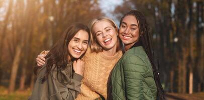 Portrait of three international young girlfriends spending time in park, panorama photo