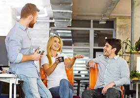 Coffee break. Young friendly colleagues talking and laughing in office, empty space photo