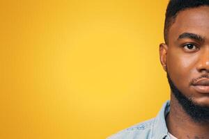 Half face portrait of confident african american man with beard on yellow studio background, free space photo
